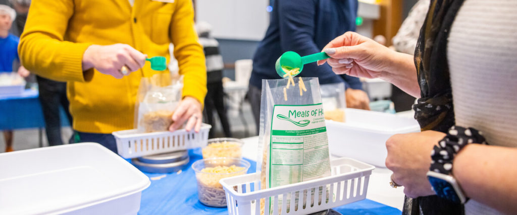 Photo of volunteers pouring noodles into a bag